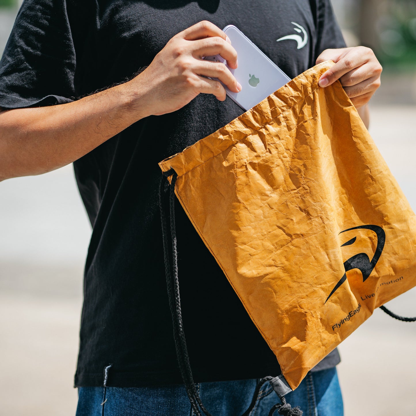 Person holding a Flying Eagle drawstring bag with a logo,