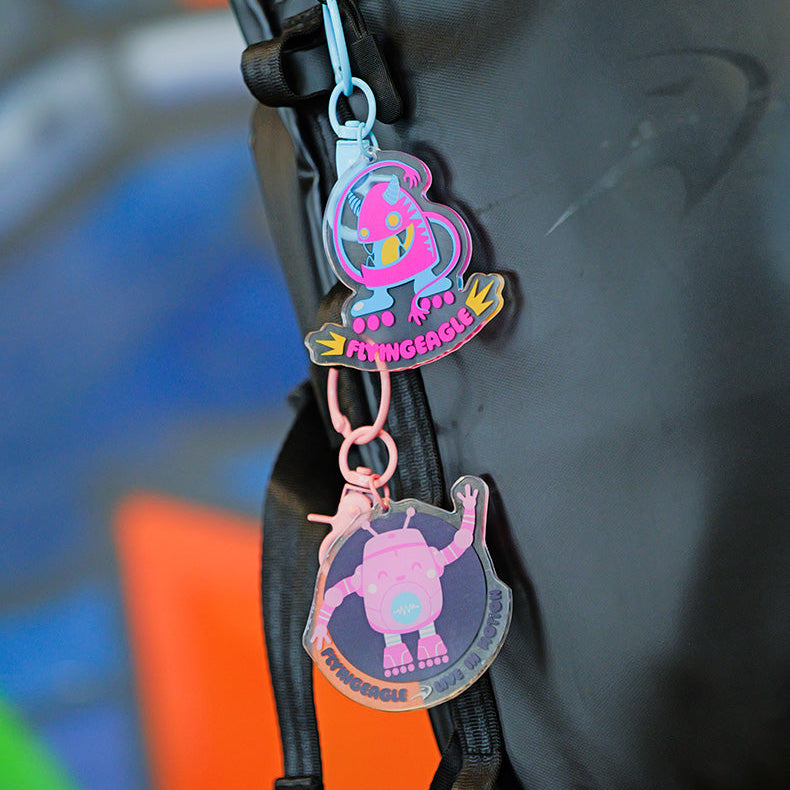 Two colorful FlyingEagle keychains hanging from a black bag 