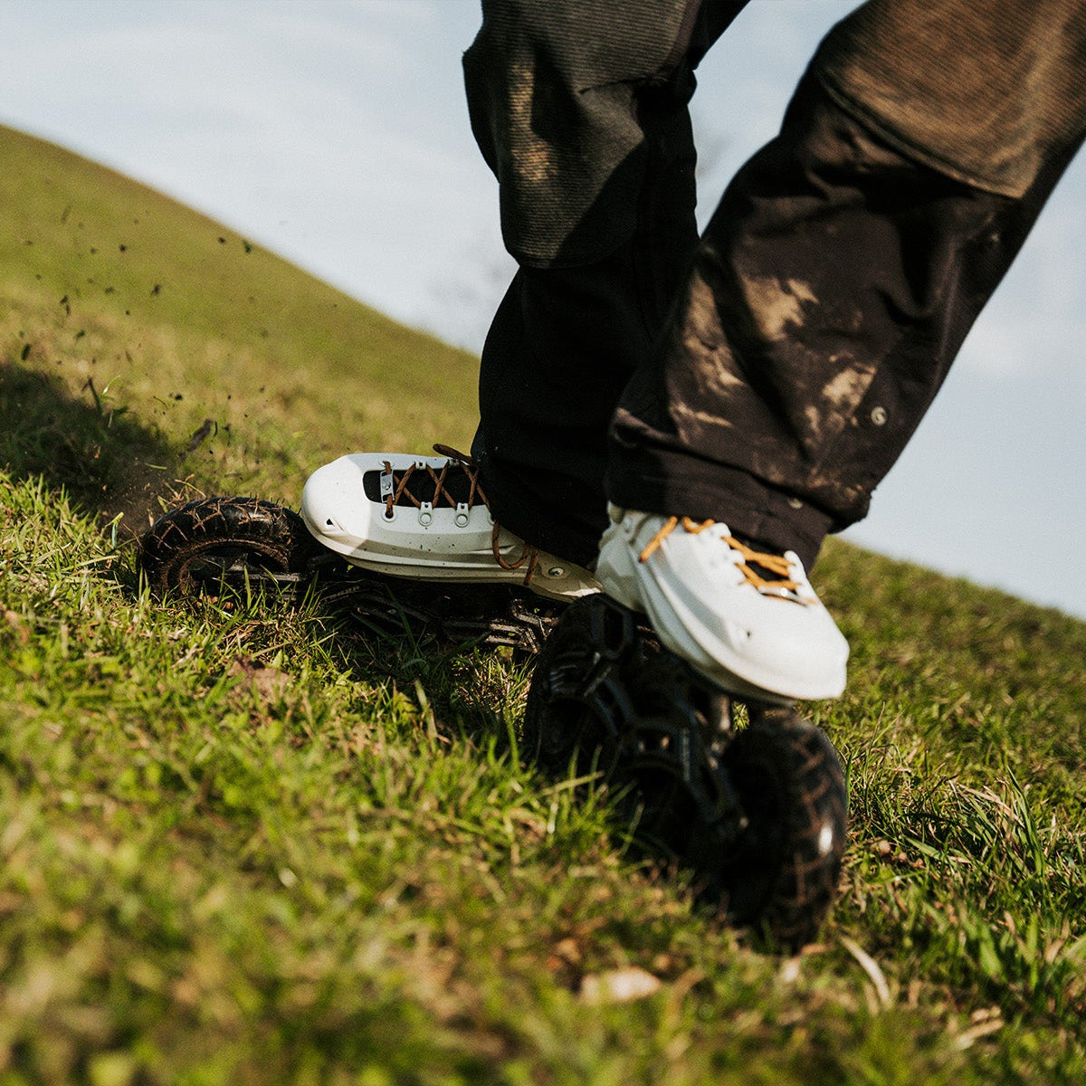 Person wearing inline skate with FlyingEagle adult black 150mm TERRA  on a grassy hill