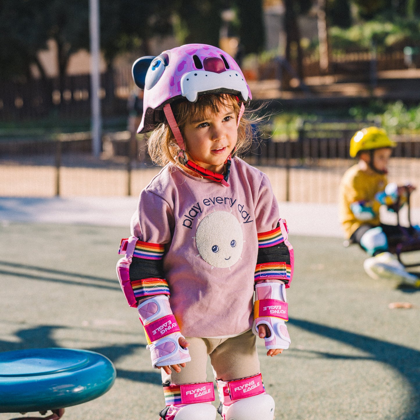 Child with FlyingEagle KT pink leopard helmet riding balance bike outdoors