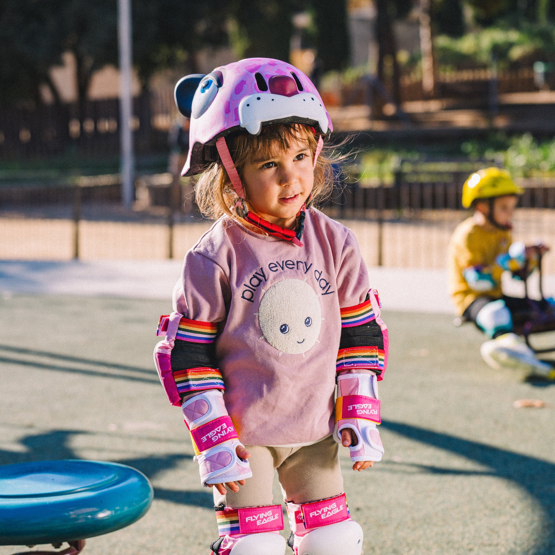 Child with FlyingEagle KT pink leopard helmet riding balance bike outdoors