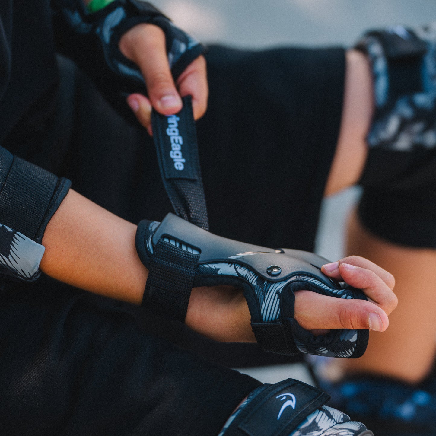 A close-up of a person wearing aFlying Eagle COBET black wrist pads, adjusting it with both hands.