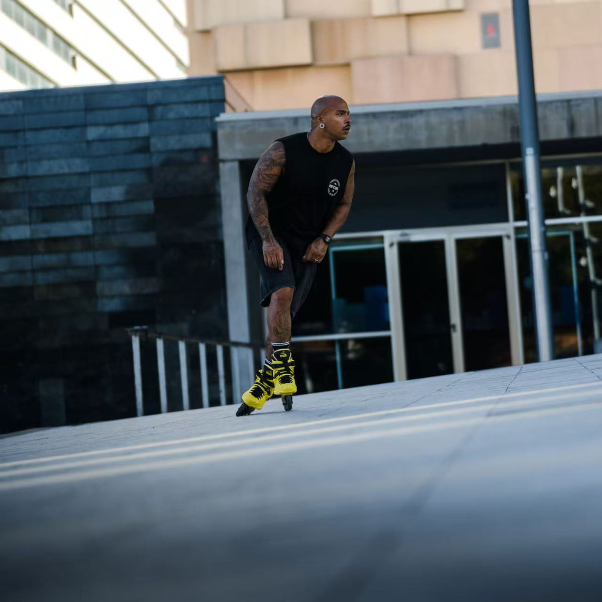 Skater with protective gear gliding on urban street with Flying Eagle REAVER S7680 Yellow Black adult inline skates 4 wheels 85A rockerable axles