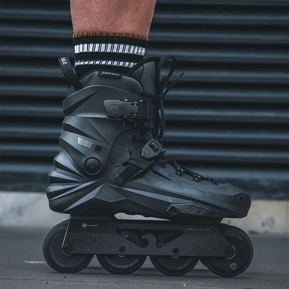 A close-up of a person's lower leg wearing FlyingEagle REAVER graphite inline skate with black wheels