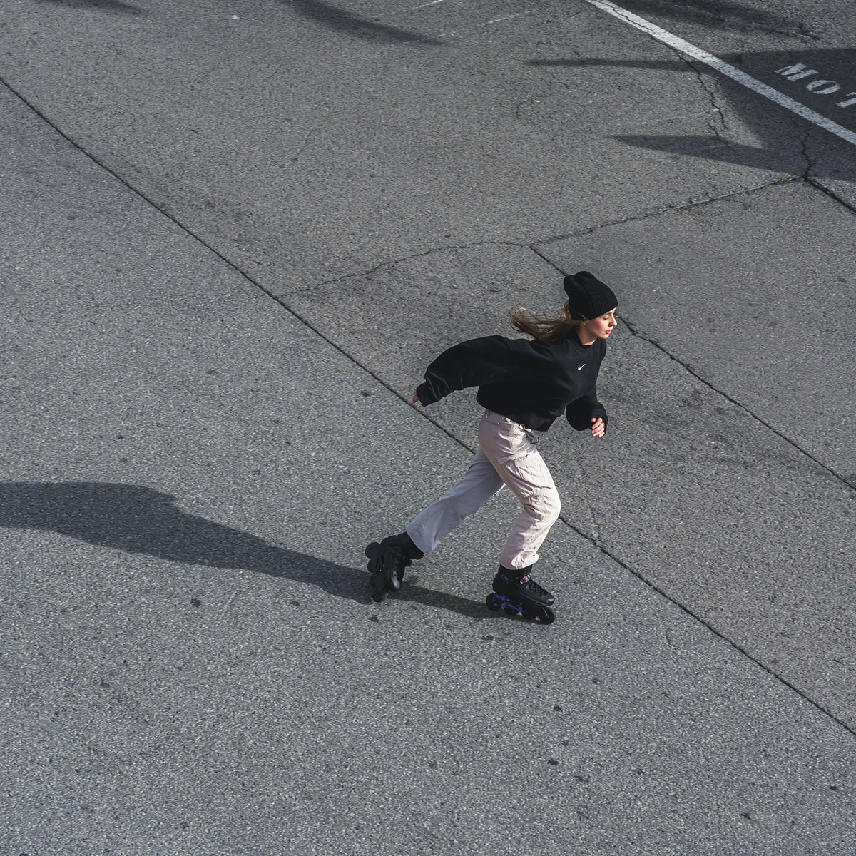 A person roller skating on a paved street, wearing FlyingEagle REAVER black‑violet inlineSkates