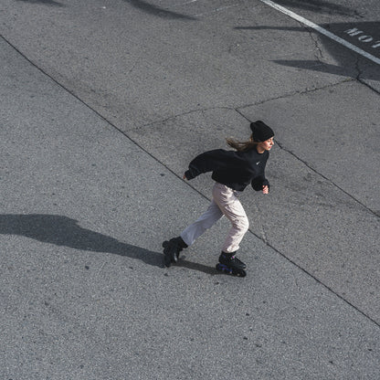 A person roller skating on a paved street, wearing FlyingEagle REAVER black‑violet inlineSkates