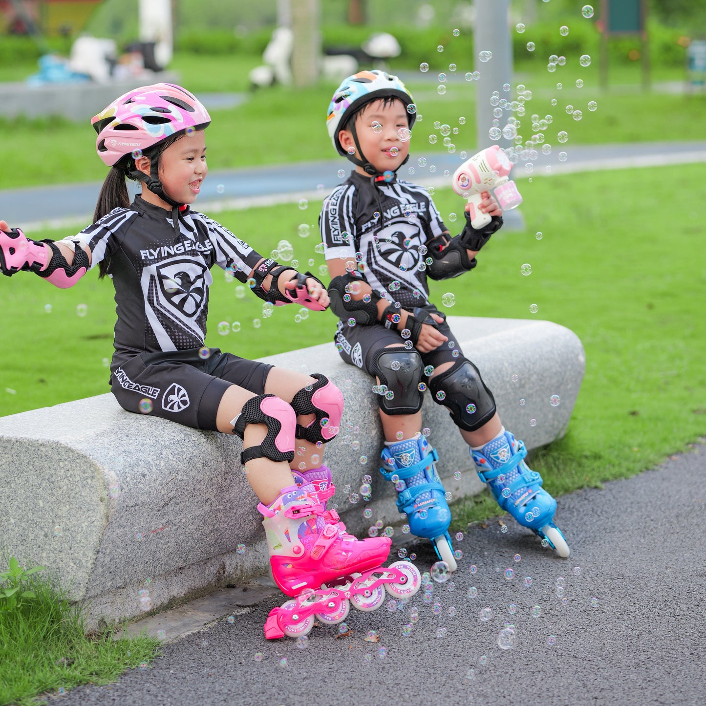 Two children in roller skates sitting on a stone bench with FlyingEagle LUMAFLY kid inline skates