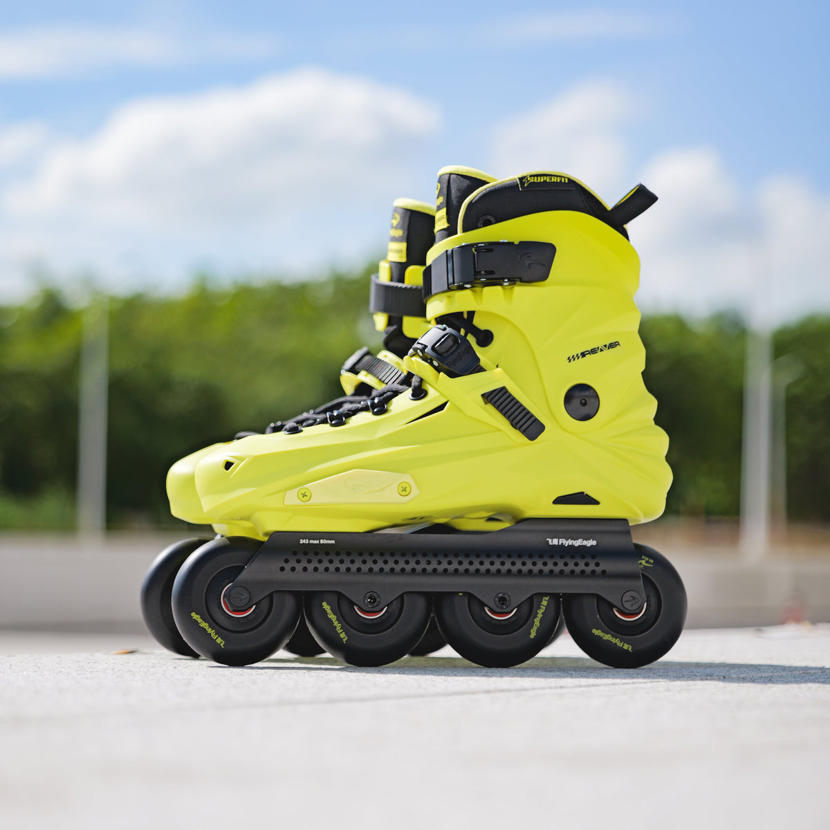 Bright yellow Flying Eagle REAVER S7680 inline skates with black wheels and straps, photographed outdoors on a paved surface with a blurred blue sky and green trees