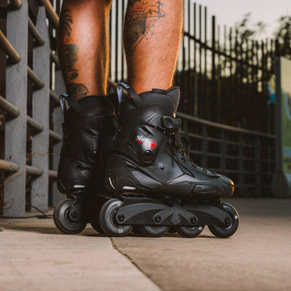 Adult putting on black Flying Eagle SHRIKE Lite hard-boot skating shoes