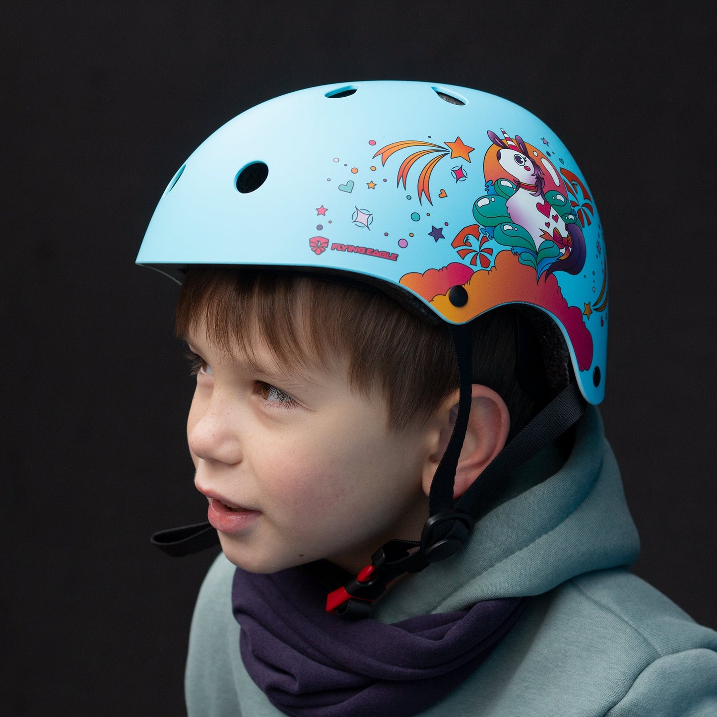 Young child with FlyingEagle RIDER JR blue helmet practicing skateboarding outdoors