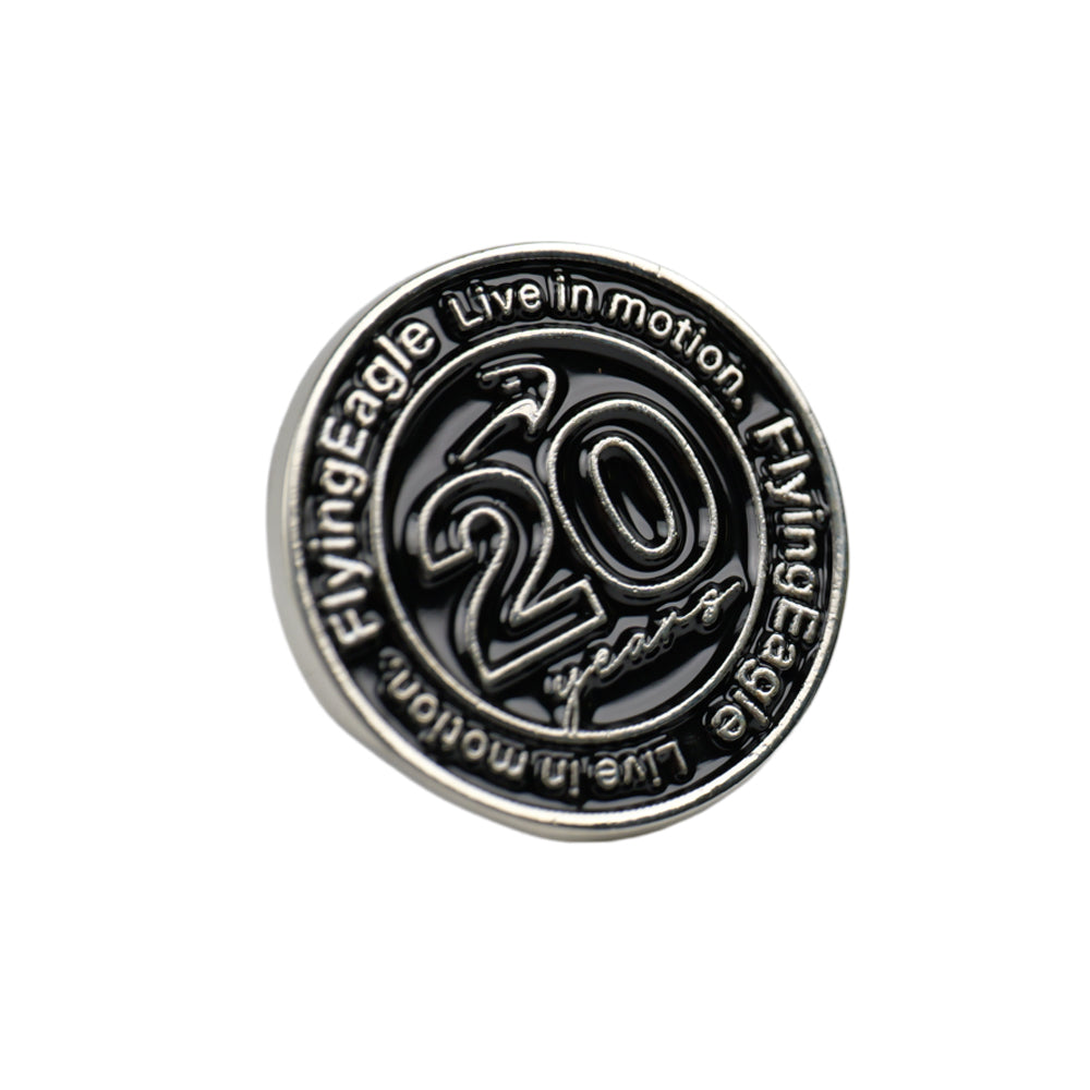 A round metallic pin or badge featuring a silver-toned border and face.