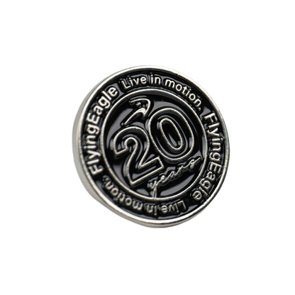 A round metallic pin or badge featuring a silver-toned border and face.